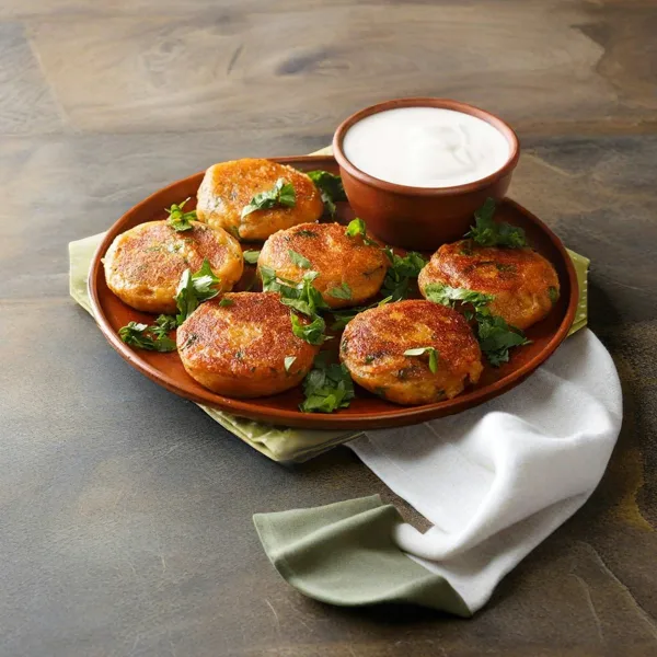 Golden shallow-fried aloo tikki potato patties served with mint and tamarind chutneys