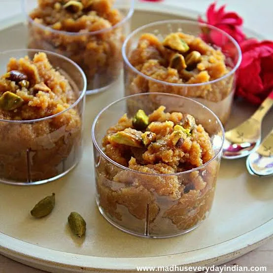 Glossy golden almond halwa in a brass dish garnished with pistachios, flaked almonds and saffron