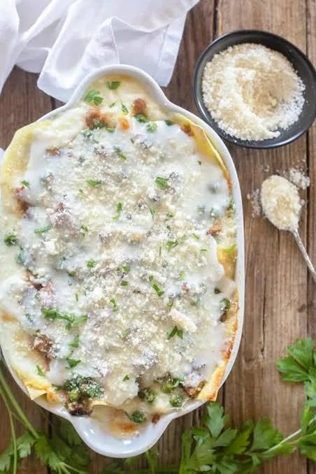 A slice of beef lasagna with visible layers of pasta, meat sauce and melted golden cheese on a white plate