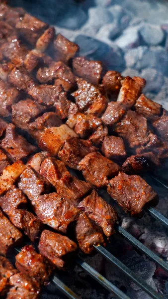 Platter of charred Bihari Boti beef strips with lemon wedges, sliced onions and paratha