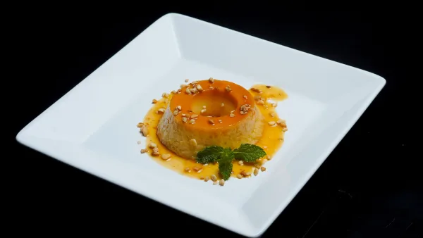 Caramel custard turned out onto a plate with glossy golden caramel sauce around it