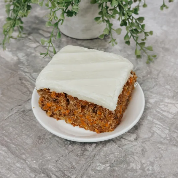 Sliced two-layer carrot cake with cream cheese frosting and chopped walnuts on a cake stand