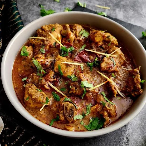 Copper karahi of chicken achari in a golden spiced gravy with green chillies, ginger and coriander, served with roti and raita