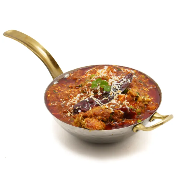 A pan of dark, peppery chicken Chettinad curry topped with curry leaves and fresh coriander, served with rice and paratha