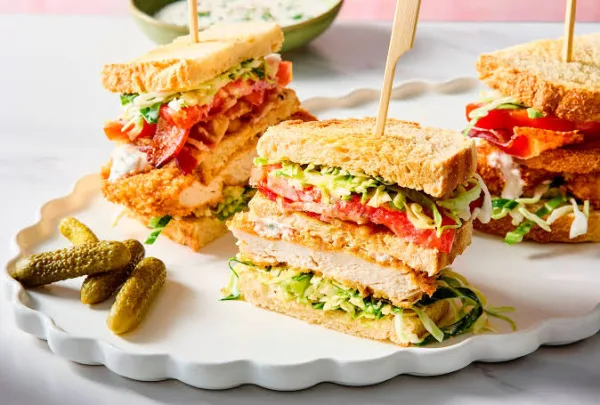 Chicken club sandwich cut into triangles showing layers of chicken, bacon, egg, tomato and lettuce on toasted bread