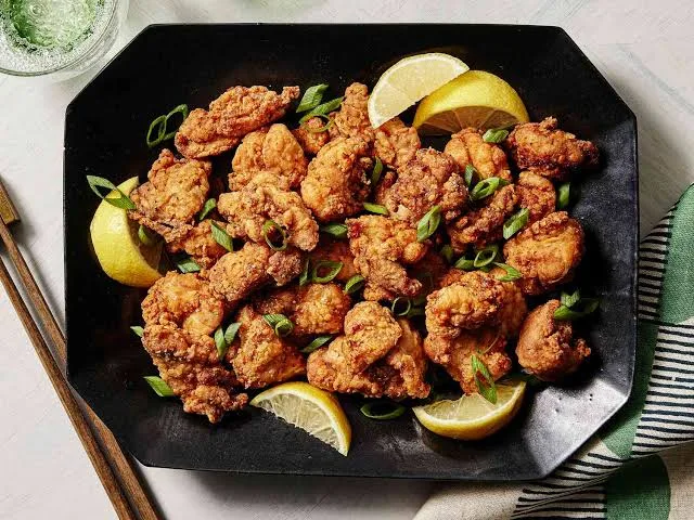 Plate of golden crispy chicken karaage with lemon wedges, mayonnaise and shredded cabbage
