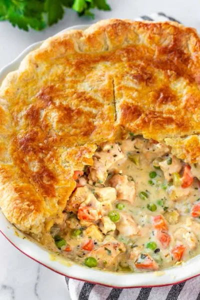 Golden chicken pot pie with a slice removed showing creamy chicken and vegetable filling