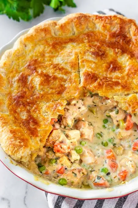 Golden chicken pot pie with a slice removed showing creamy chicken and vegetable filling