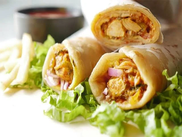 Chicken roll parathas with one cut open to show spiced chicken, mint yogurt sauce and onions
