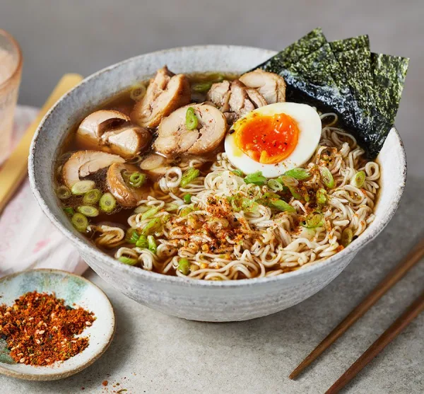 Bowl of chicken shoyu ramen with soy egg, shredded chicken, spinach, sweetcorn and nori in clear brown broth