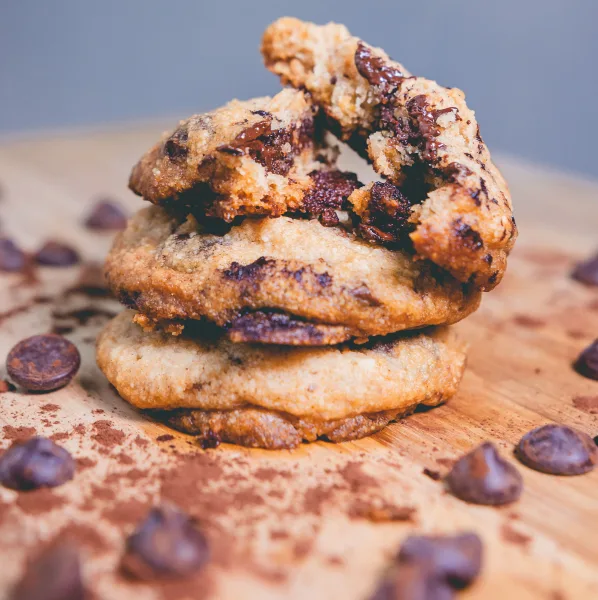Chewy chocolate chip cookies on a wooden board with a glass of milk