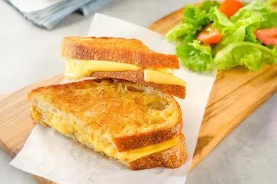 Grilled cheese sandwich cut in half with melted cheese stretching between the golden toasted halves
