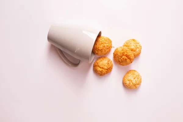 Golden coconut macaroons, some dipped in dark chocolate, on a white plate