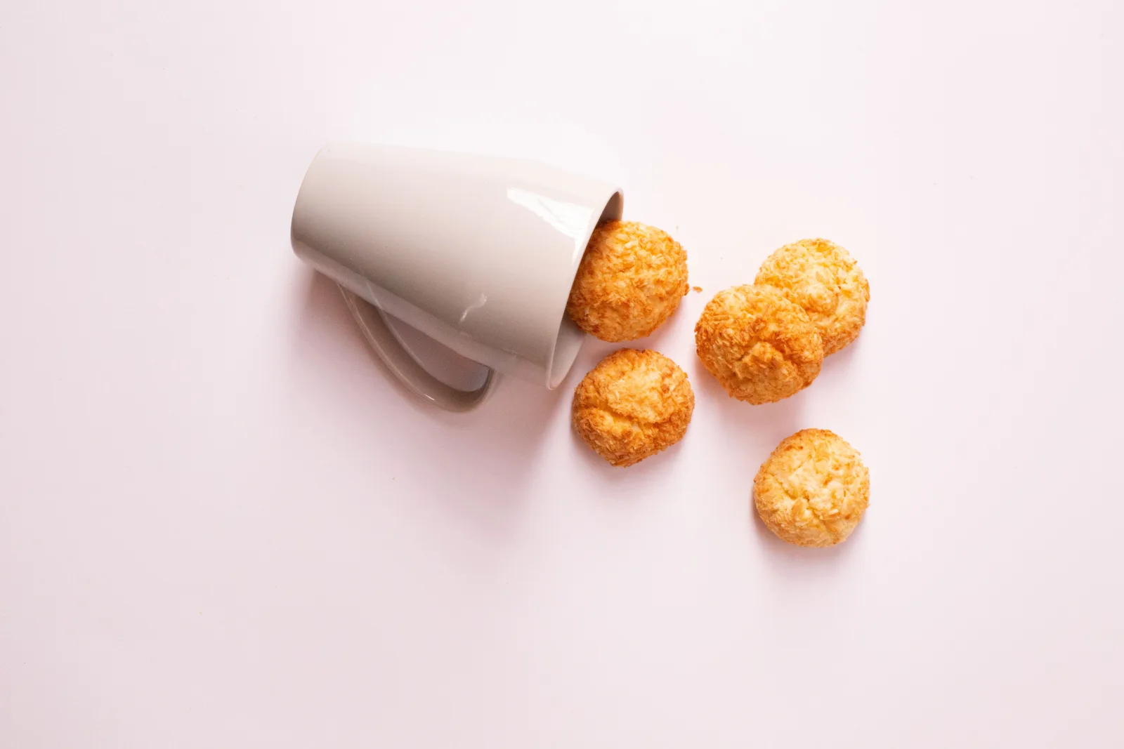 Golden coconut macaroons, some dipped in dark chocolate, on a white plate