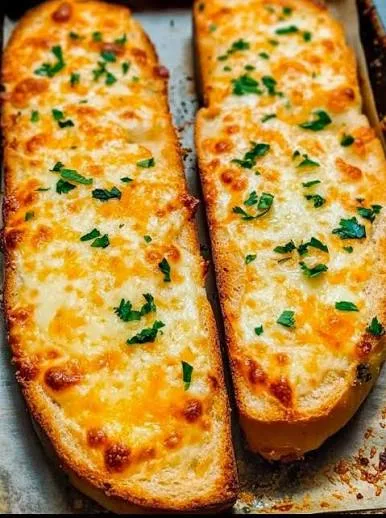 Sliced golden garlic bread topped with melted mozzarella and parsley on a wooden board
