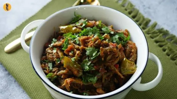 Pan of karelay pyaz with browned bitter gourd rounds, golden onions and green chillies, served with chapatis