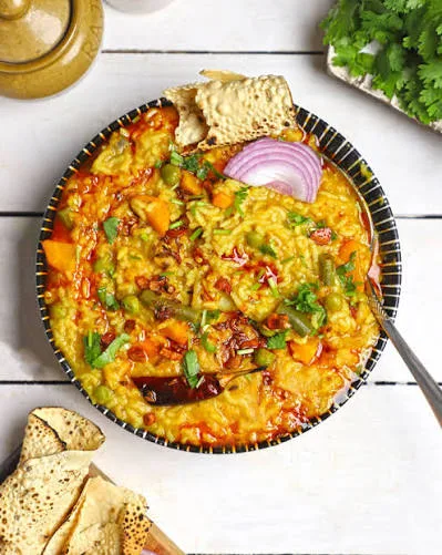 A bowl of golden moong daal khichdi topped with melted ghee, fried garlic and coriander