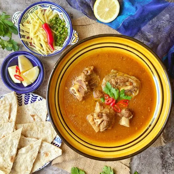 A clay pot of rich Kunna Gosht mutton curry topped with ginger and coriander, served with naan