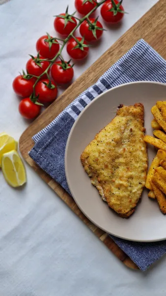Golden crispy Lahori fried fish pieces on a platter with lemon wedges, onion rings and green chutney