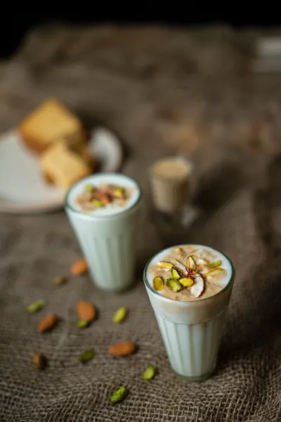 Glasses of sweet and salted lassi garnished with pistachios, malai, roasted cumin and mint