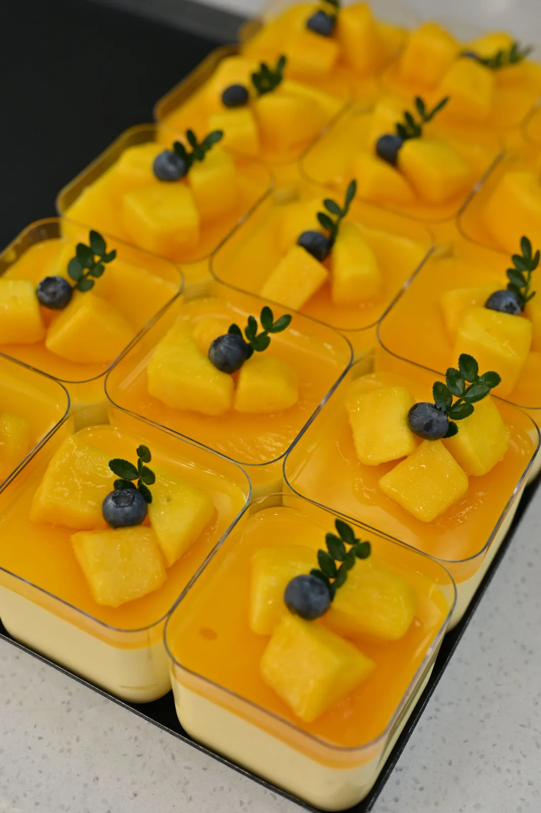 Glasses of smooth golden mango mousse topped with diced mango and mint leaves