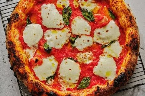 Margherita pizza with melted mozzarella and fresh basil on a wooden board