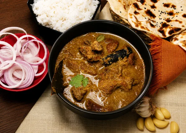 Mutton chops in thick red-brown masala with ginger, green chillies and coriander in a karahi