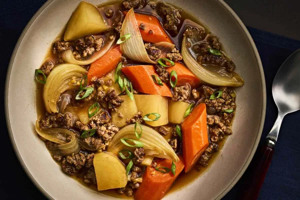 Bowl of Japanese nikujaga beef and potato stew with carrots, onion and green peas