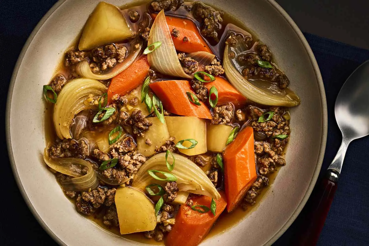 Bowl of Japanese nikujaga beef and potato stew with carrots, onion and green peas