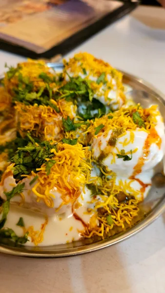 Platter of papri chaat topped with chickpeas, yogurt, chutneys, sev and pomegranate seeds