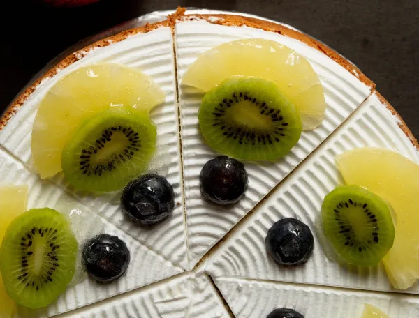 Pineapple upside-down cake with glossy caramelised pineapple rings and cherries, with one slice cut