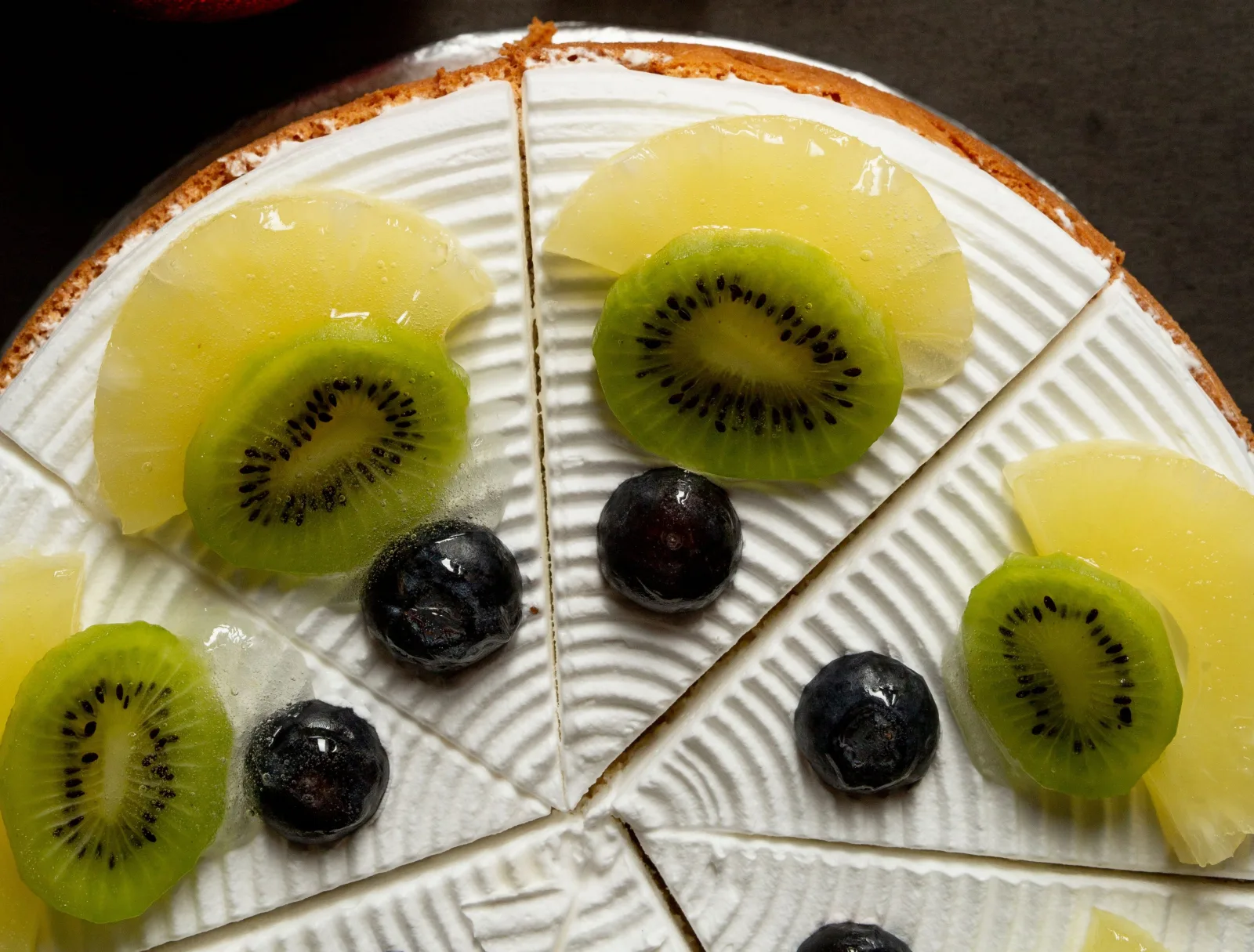 Pineapple upside-down cake with glossy caramelised pineapple rings and cherries, with one slice cut
