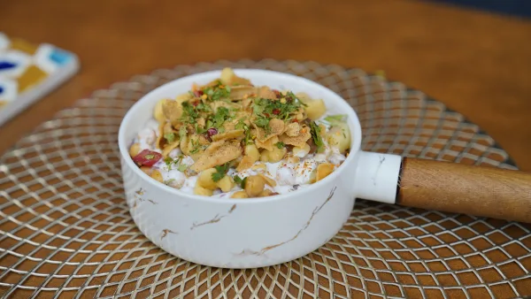 A bowl of sabudana khichdi with tapioca pearls, potato, peanuts and coriander beside a lemon wedge