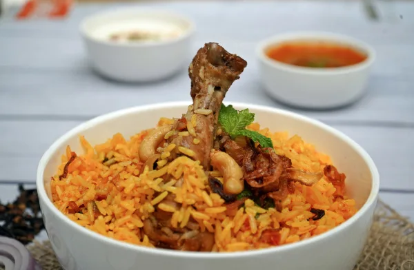 A pot of Sindhi biryani with saffron rice, potatoes, dried plums, green chillies and fresh herbs
