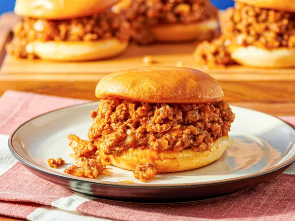 Sloppy Joe sandwiches with saucy beef filling on toasted buns served with pickles and potato wedges