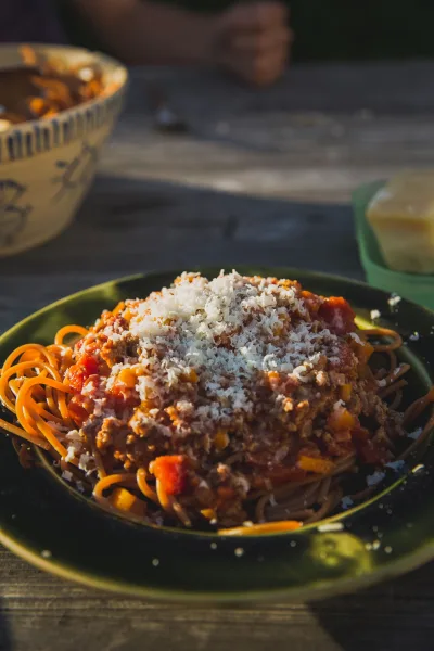 A bowl of spaghetti topped with rich beef and tomato Bolognese sauce, grated Parmesan and fresh basil
