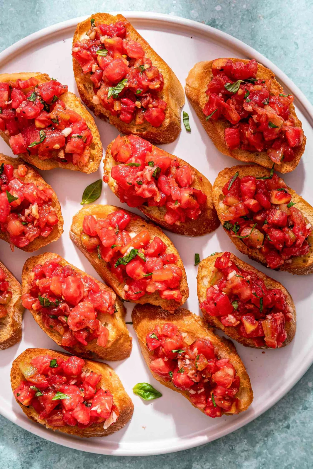 Toasted bread slices topped with diced tomatoes and fresh basil on a wooden board