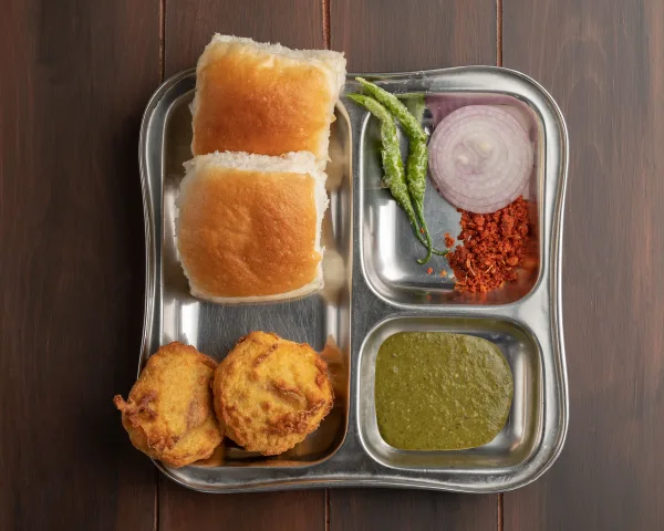 Vada pav with golden potato fritters in toasted buns, green chutney and fried green chillies