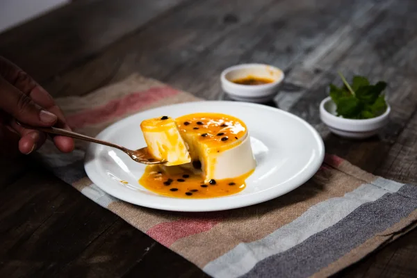 Vanilla panna cotta topped with strawberry sauce and fresh strawberries on a white plate