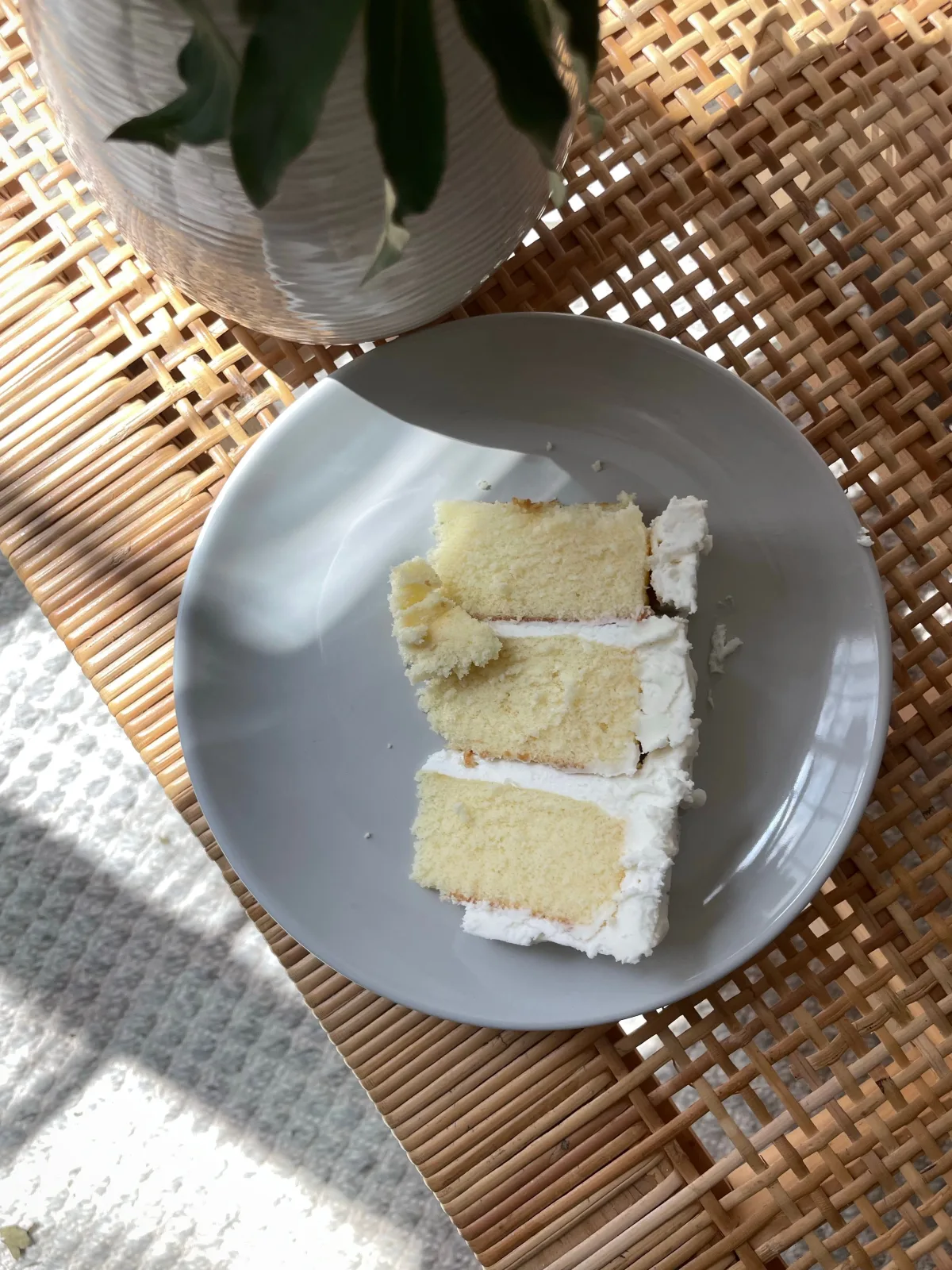 Sliced vanilla sponge cake with jam and buttercream filling on a white cake stand