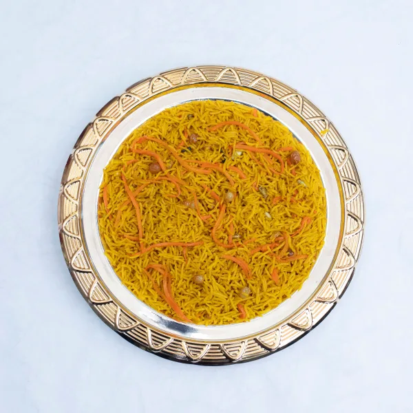 A serving dish of golden zarda sweet rice topped with sliced pistachios, almonds and raisins