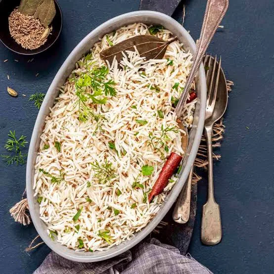 A bowl of fluffy zeera rice with visible cumin seeds and fresh coriander