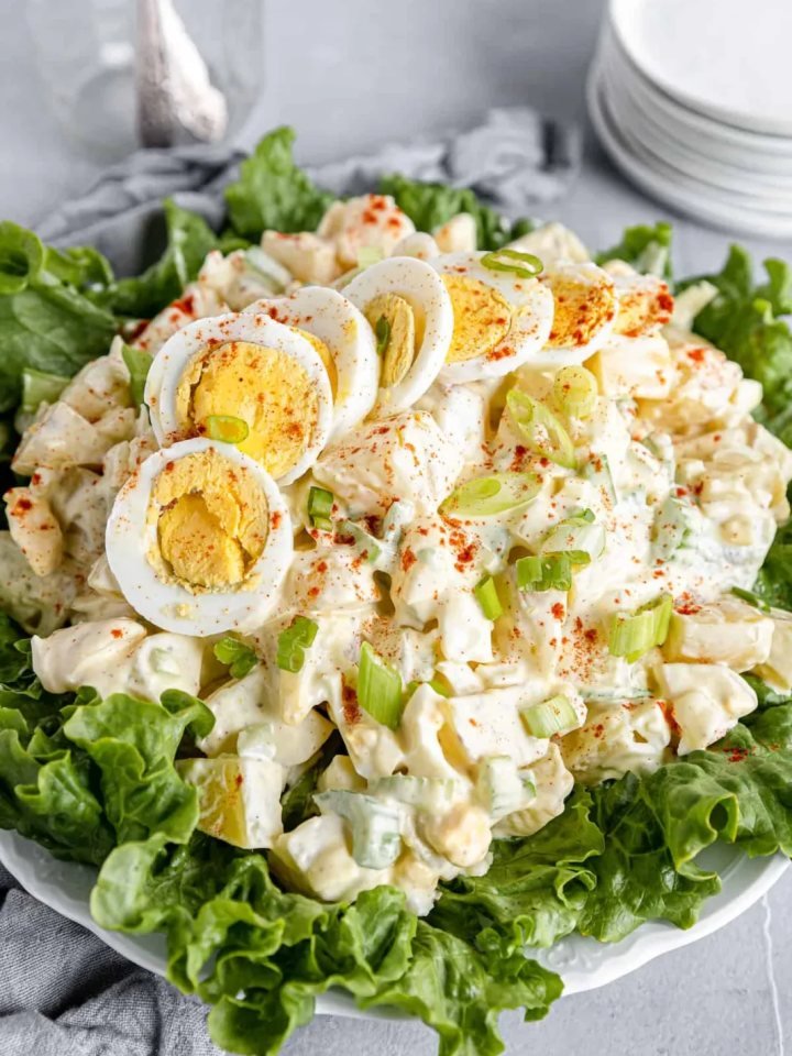 Bowl of creamy American potato salad topped with egg slices, paprika and parsley