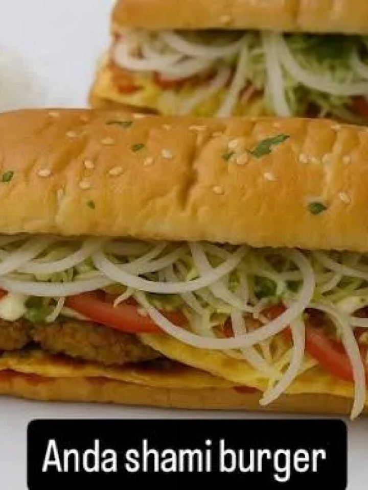 Anda shami burger with a golden shami patty, fried egg, fresh salad and chilli mayo in a toasted bun on a wooden board