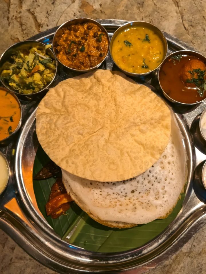 Golden lacy appams with fluffy white centres served with vegetable stew on a banana leaf