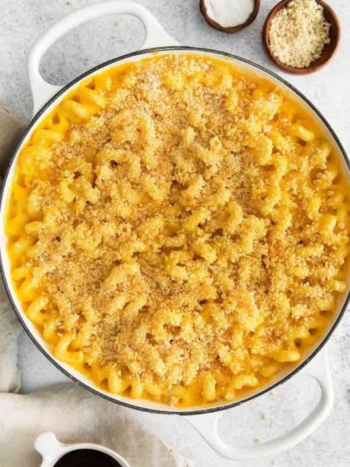 Golden baked macaroni and cheese in a baking dish with a crisp breadcrumb topping and a creamy spoonful lifted out