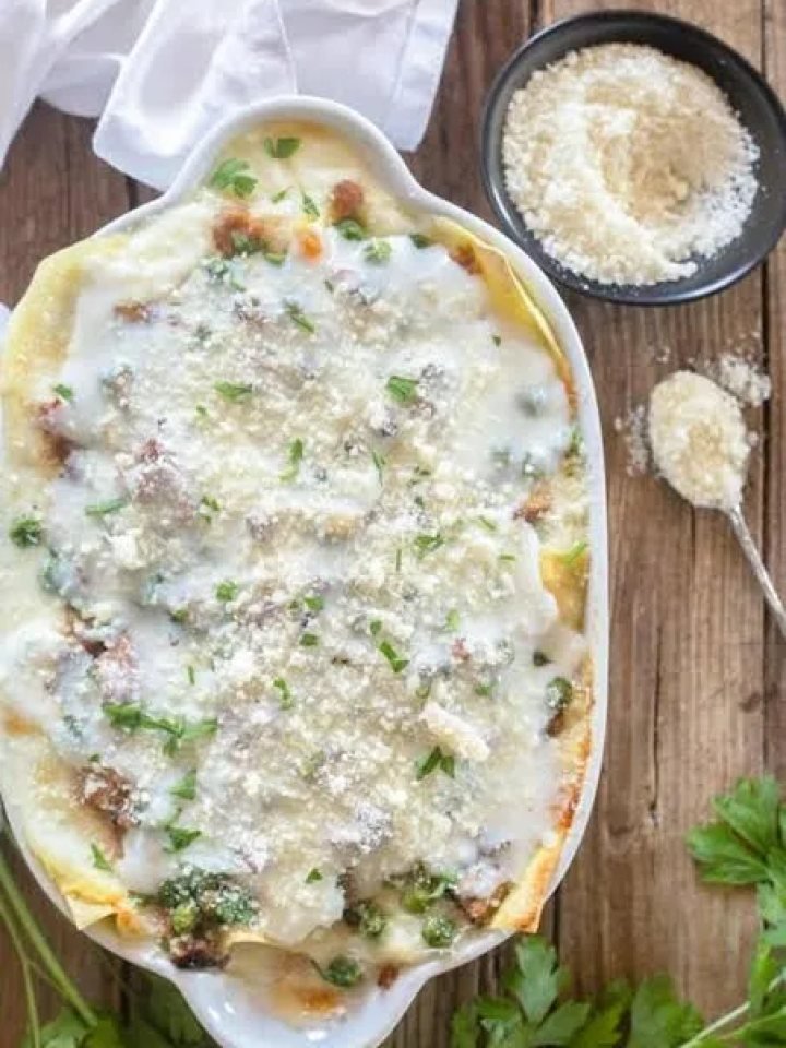 A slice of beef lasagna with visible layers of pasta, meat sauce and melted golden cheese on a white plate