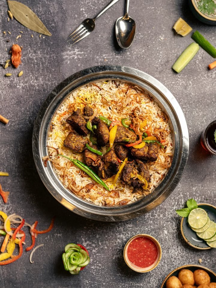 Pot of Pakistani beef pulao with golden basmati rice, beef pieces, browned onions and fresh herbs