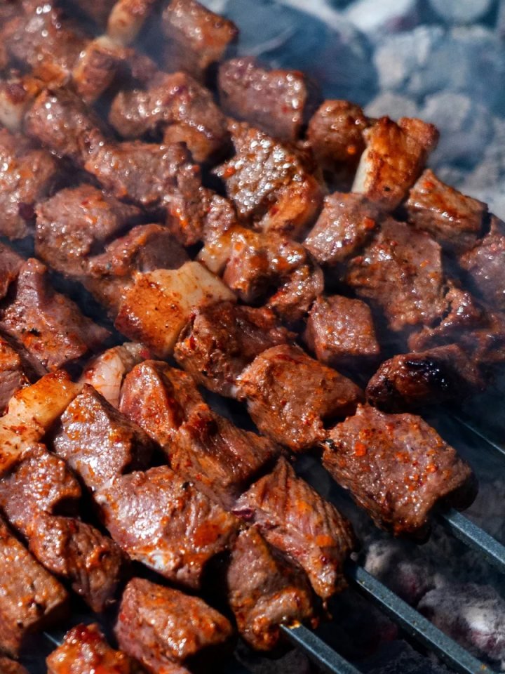 Platter of charred Bihari Boti beef strips with lemon wedges, sliced onions and paratha