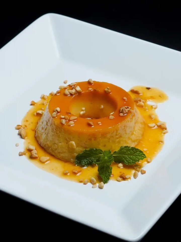 Caramel custard turned out onto a plate with glossy golden caramel sauce around it